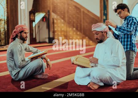Eine Gruppe von Muslimen, die das heilige Buch des Korans während des muslimischen Feiertags von Ramadan in einer modernen Moschee las Stockfoto