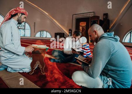 Eine Gruppe von Muslimen, die das heilige Buch des Korans während des muslimischen Feiertags von Ramadan in einer modernen Moschee las Stockfoto
