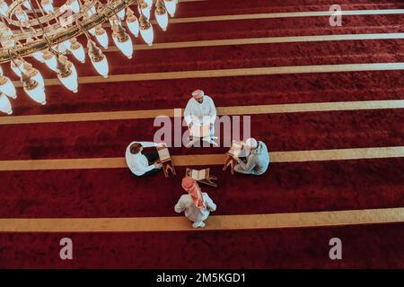 Eine Gruppe von Muslimen, die das heilige Buch des Korans während des muslimischen Feiertags von Ramadan in einer modernen Moschee las Stockfoto