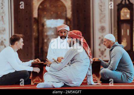 Eine Gruppe von Muslimen, die das heilige Buch des Korans während des muslimischen Feiertags von Ramadan in einer modernen Moschee las Stockfoto