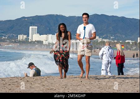 Leute genießen einen Spaziergang am Venice Beach mit der Skyline von Santa Monica im Hintergrund. Stockfoto