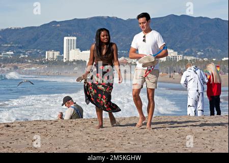 Leute genießen einen Spaziergang am Venice Beach mit der Skyline von Santa Monica im Hintergrund. Stockfoto