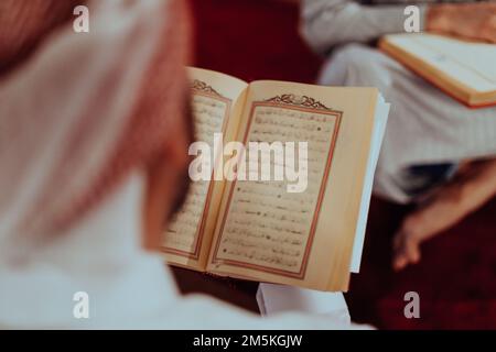 Eine Gruppe von Muslimen, die das heilige Buch des Korans während des muslimischen Feiertags von Ramadan in einer modernen Moschee las Stockfoto