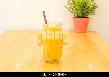 Ein reifer Ananas-Smoothie in einer Glasschüssel auf einem Kiefernholztisch Stockfoto