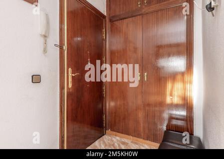 Halle eines Hauses mit gepanzerter Tür und eingebauter Garderobe mit lackiertem Sapelenholz Stockfoto