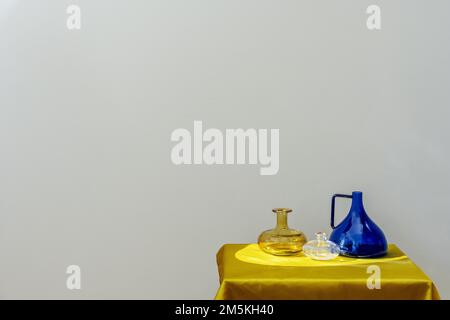 Dekorative Glasgefäße in verschiedenen Farben auf einer goldenen Stoffstruktur Stockfoto