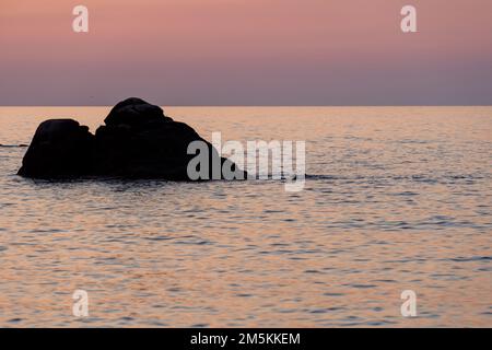 Tropische, farbenfrohe Landschaft bei Sonnenaufgang. Naturlandschaft. Tropische Inselküste. Wunderschöne Aussicht auf die orangefarbene Sonnenuntergangslandschaft mit Felsen Stockfoto