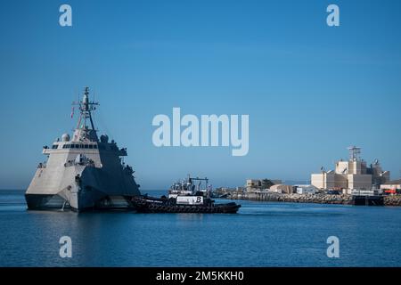 Die USS Kansas City (LCS 22) passiert das Naval Surface Warfare Center, die von der Port Hueneme Division betriebene Surface Warfare Engineering Facility, die bei der Ankunft von Schleppbooten geführt wird. Stockfoto