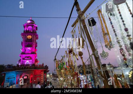 Jodhpur, Rajasthan, Indien - 19.10.2019 : Gold- und versilberte Ornamente werden auf dem berühmten Sardar-Markt und dem Ghanta-Ghar-Uhrenturm dahinter verkauft Stockfoto