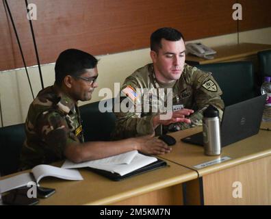 USA Army Major Trevor Caldwell, Delegierter der Nationalgarde Oregons und Generalanwalt (JAG) Offizier, spricht mit seinem bangladeschischen Amtskollegen über rechtliche Fragen, während er am 23. März 2022 im BIPSOT-Zentrum des Bangladesch Institute of Peace Support Operation Training (BIPSOT) in Dhaka, Bangladesch, tätig war. Delegierte der Oregon National Guard nehmen an der Übung Tiger Lightning 2022 Teil, einer bilateralen Übung, die von den USA gesponsert wird Indo-Pacific Command und Gastgeber der Streitkräfte Bangladeschs, Stärkung der Verteidigungsbereitschaft Bangladeschs, Aufbau operativer Interoperabilität und Stärkung der Partnerschaft zwischen den beiden Stockfoto