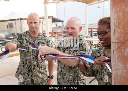 CAMP LEMONNIER, Dschibuti (23. März 2022) USA Marinekapitän David Faehnle (Zentrum), kommandierender Offizier des Camps Lemonnier, Dschibuti (CLDJ), USA Sean Baney, Generalkommando der Marine, und Brandi N. Harris, Senior Chief Logistics Specialist, schnitten während einer Zeremonie des Joint Forces Diversity & Inclusion Committee zum CLDJ ein Band, um ihre Errungenschaft als nicht-föderale Einheit (NFE), eine sich selbst tragende Organisation auf einer militärischen Einrichtung, zu feiern. CLDJ dient als Expeditionsbasis für US-Streitkräfte, die Schiffe, Flugzeuge und Personal unterstützen, die die Sicherheit gewährleisten Stockfoto