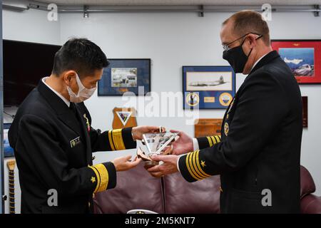 MISAWA, Japan (23. März 2022) – Kapitän Paul A. Hockran, rechts, Befehlshaber der Naval Air Facility (NAF) Misawa, überreicht ein Geschenk an die Marine Self-Defense Force Rear ADM Takumaru Furihata, Befehlshaber, Fleet Air Wing 2. NAF Misawa bietet Unterstützung und Dienstleistungen für die Luftfahrt- und Bodenlogistik in allen permanenten und transienten USA Navy und USA Marinekorps in Nordjapan. Stockfoto