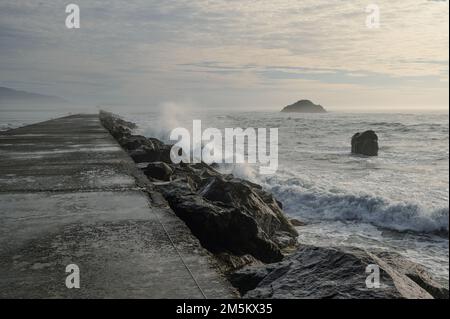 Eine große Meereswelle traf an einem stürmischen Tag auf einem Steg ein. Stockfoto