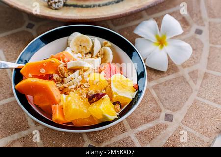 Gesunde Frühstückschüssel mit Joghurt und tropischen Früchten auf dem Steintisch Stockfoto