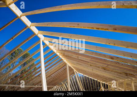 Konstruktion eines neu gebauten Holzdachträgers, der aus einem Rahmen mit Stäben zusammengebaut wird Stockfoto