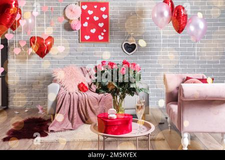 Tisch mit Rosenblumen, Verlobungsring, Geschenk und Gläser Champagner im Zimmer, dekoriert zum Valentinstag Stockfoto