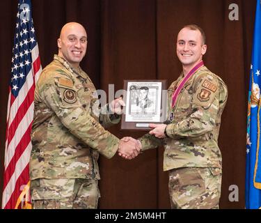 Chief Master Sgt. Joshua Malyemezian überreicht Senior Airman David Schweinberg während der Abschlusszeremonie der Airman Leadership School Class 22-C am 24. März 2022 auf dem Luftwaffenstützpunkt Wright-Patterson, Ohio, mit einem Distinguished Graduate Award. Mit den Distinguished Graduate Awards werden Studenten ausgezeichnet, die in den besten 10 Prozent der Klasse in den Bereichen Akademiker, nachweisliche Führungsqualitäten und Leistungen liegen. Stockfoto