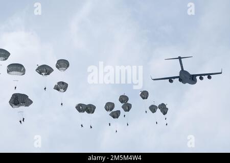 USA Fallschirmjäger des 4. Infanterie-Brigaden-Kampfteams (Airborne), 25. Infanteriedivision, USA Army Alaska, springen Sie aus den USA Luftwaffe C-17 Globemaster III, zugewiesen zum 62. Luftwaffenflügel, Joint Base Lewis-McChord, Washington, über der Malemute Drop Zone, während des Flugeinsatzes in der Joint Base Elmendorf-Richardson, Alaska, 24. März 2022. Das 4-25. IBCT ist das einzige bordseitige Kampfteam im Pacific Theater und führt regelmäßig Schulungen durch, um die Einsatzbereitschaft in einer arktischen Umgebung aufrechtzuerhalten. Stockfoto