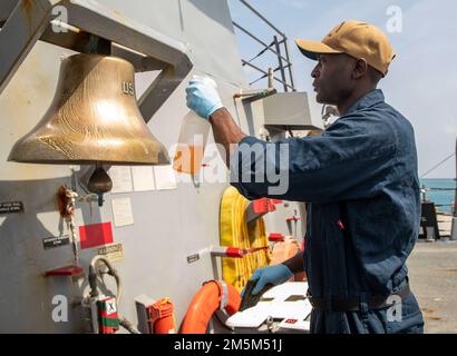 OKINAWA, Japan (24. März 2022) Culinary Specialist 2. Class Tyrie Mordecai aus Savannah, Georgia, sprüht Reinigungslösung auf die Schiffsglocke an Bord des Arleigh Burke-Class Guided Missile Destroyer USS Ralph Johnson (DDG 114). Ralph Johnson ist der Task Force 71/Destroyer Squadron (DESRON) 15, dem größten nach vorn verlegten DESRON der Marine, und der Hauptstreitkraft der US-7.-Flotte zugewiesen. Stockfoto