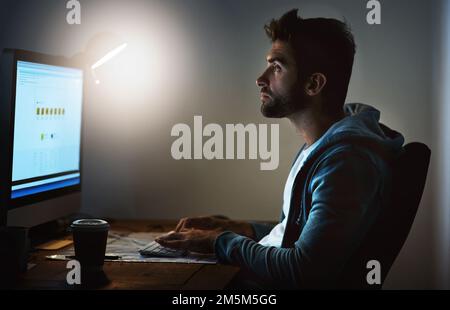 Bis spät in die Nacht arbeiten. Ein junger Designer, der lange im Büro arbeitet. Stockfoto