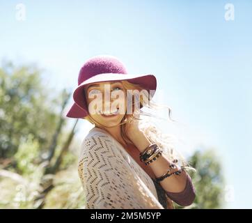 Glücklich und frei ist der einzige Weg für mich. Porträt einer attraktiven jungen Frau mit Sonnenhut, die draußen steht. Stockfoto