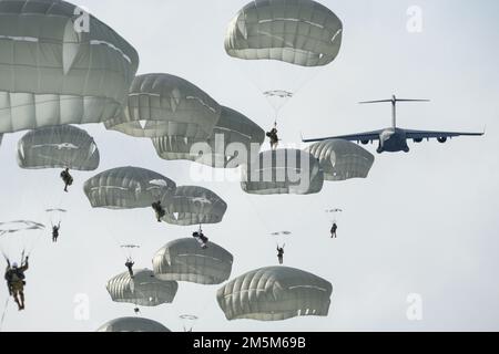 Fallschirmjäger der 4. Infanterie-Brigade-Kampfeinheit (Airborne), 25. Infanteriedivision, USA Army Alaska, nach dem Sprung aus den USA Air Force C-17 Globemaster III über Malemute Drop Zone während des Flugtrainings auf der Joint Base Elmendorf-Richardson, Alaska, 24. März 2022. Armee- und Luftwaffeneinheiten bilden regelmäßig zusammen aus, um die Fähigkeit zur gemeinsamen Einsatzbereitschaft in einem arktischen Umfeld zu stärken und aufrechtzuerhalten. Flugzeuge des 62. Luftwaffenflügels, Joint Base Lewis-McChord, Washington, leisteten Luftunterstützung für das Training. Stockfoto