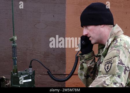 USA Army 1. LT. Chad Petuoglu, Fallschirmjäger der Hundefirma, 3. Bataillon, 509. Parachute Infanterie-Regiment, 4. Infanterie-Brigade-Kampfteam (Airborne), 25. Infanterie-Division, USA Army Alaska, benutzt ein Funkgerät an einem Munitionslieferpunkt während des Stress-Feuertrainings auf dem Sportfeuergelände auf der Joint Base Elmendorf-Richardson, Alaska, 24. März 2022. Die Soldaten der Dog Company wurden auf schnelle Feuerbereitschaft untersucht, während sie ein simuliertes Gefechtsfeldopfer sicher evakuierten, indem sie improvisierten Abfall von SKED und Kontakt über gefährlichen Schlamm und vereisten Boden brachen. (USA Luftpressen Stockfoto