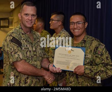 220325-N-EJ241-1008 DIEGO GARCIA, Britisches Territorium im Indischen Ozean (25. März 2022) – Fähnrich Cody R. Fulton, Food Service Officer für Naval Support Facility (NSF) Diego Garcia, erhält während der Quartale eine Navy and Marine Corps Achievement Medal von Kapitän Richard D. Payne, kommandierender Offizier der NSF Diego Garcia. NSF Diego Garcia bietet Logistik-, Service-, Freizeit- und administrative Unterstützung für US-Streitkräfte und Alliierte, die im Indischen Ozean und am Arabischen Golf stationiert sind. Stockfoto