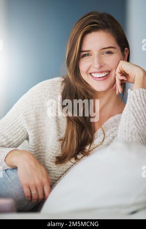 Nehmen Sie sich Zeit, um die einfachen Dinge im Leben zu genießen. Eine junge Frau, die sich zu Hause auf ihrem Sofa entspannt. Stockfoto