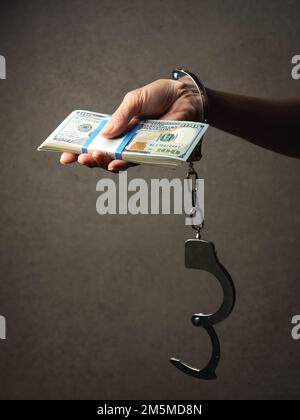 Handschellen an Handgelenken, Dollarscheine Stockfoto