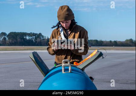 Ein Mitglied der Waffenladungscrew, das dem 335. Kampfgeschwader zugeteilt ist, inspiziert inerte Bombeneinheiten, bevor sie sie während eines jährlichen Ladungswettkampfs am Seymour Johnson Air Force Base, North Carolina, am 25. März 2022 auf einen F-15E Strike Eagle laden. Während des Wettbewerbs müssen die Crews Checklisten befolgen, um sicherzustellen, dass die Waffen sicher und korrekt zusammengesetzt und installiert werden. Stockfoto