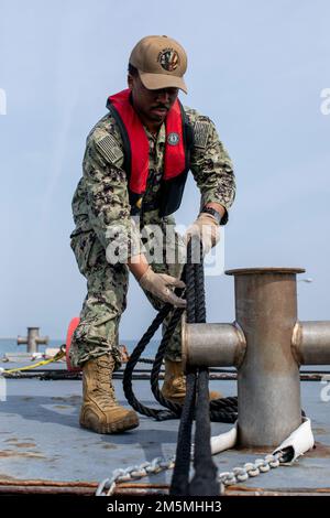 USA Navy Petty Officer Third Class Caylon Williams, ein Bootsmann, der mit dem Hafenbetrieb der Marine Corps Air Station Iwakuni in Verbindung steht, legt ein Boot am MCAS Iwakuni, Japan, an, 25. März 2022. Das Festmachen von Schiffen ist etwas, das jeder Seemann, der im Hafen arbeitet, in der Grundausbildung lehrt. Der Tiefwasserhafen von MCAS Iwakuni spielt eine wesentliche Rolle bei der Versorgung der Einheiten der Flugstation mit der erforderlichen Ausrüstung und bei der Unterstützung verschiedener Schiffe, die durch die Region Indo-Pazifik fahren. Stockfoto