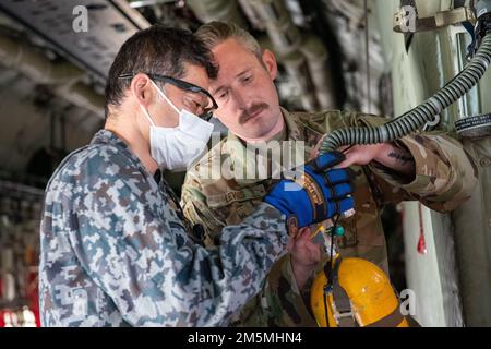 Staff Sgt. Fletcher Lewis, 36. Lufttransport-Geschwader, demonstriert Staff Sgt. Kenichirou Suda, Japan Air Self-Defense Force-Mitglied, wie die USA Air Force führt Inspektionen in einem C-130J Super Hercules während einer bilateralen NCO Immersion auf dem Luftwaffenstützpunkt Yokota, Japan, am 25. März 2022 durch. Das bilaterale Austauschprogramm ist ein einwöchiges Programm, in dem US-amerikanische und japanische Airmen mit dem Partner zusammenarbeiten, um Ideen auszutauschen und voneinander zu lernen. Stockfoto