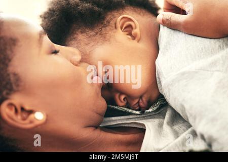 Ich liebe es, ihm beim Schlafen zuzusehen. Ein süßer Junge, der in den Armen seiner Mutter eingeschlafen ist. Stockfoto