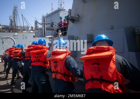 220326-N-KW492-1339 SEELEUTE DER PHILIPPINEN SEE (26. März 2022) ziehen während einer Wiederauffüllung auf See mit dem Trockenfracht- und Munitionsschiff USNS Cesar Chavez (T-AKE 14) eine Leine, die die Betankungssonde näher an die Arleigh-Burke-Raketenzerstörerin USS Milius (DDG 69) heranzieht. Milius ist der Destroyer Squadron (DESRON) 15, der größten nach vorn stationierten DESRON der Navy, und der wichtigsten Kampftruppe der US-7.-Flotte zugewiesen und unterstützt derzeit ein freies und offenes Indo-Pacific. Stockfoto