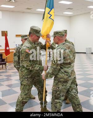 (Von links nach rechts) Oberst John Pippy, scheidender Befehlshaber der Manöver-Verstärkung-Brigade 55., erhält die Brigadefarben von Kommandosgt. Major Shawn Phillips, Kommandosergeant Major der MEB 55., während der MEB-Zeremonie 55. in Fort Indiantown Gap, Pa, am 26. März 2022. Pippy übernahm im März 2019 das Kommando über den MEB 55. und führte die Brigade durch schwierige Herausforderungen wie COVID und mehr Stockfoto