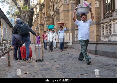 Gepäckträger mit Fischkörben auf dem Kopf, am Chhatrapati Shivaji Maharaj Terminus (CMST) in Mumbai, Indien, um die Körbe mit dem Zug weiterzuleiten Stockfoto