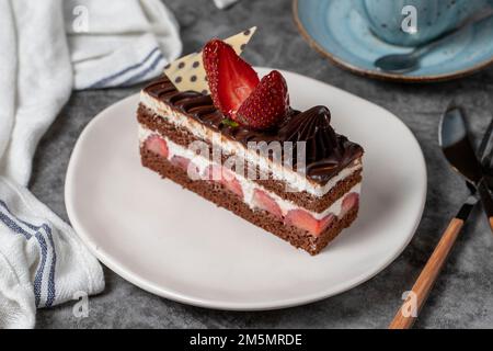 Erdbeeren- und Schokoladenkuchen auf dunklem Hintergrund. Ein Stück Schokoladenkuchen. Backwaren. Schließen Stockfoto