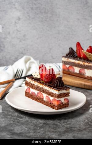 Erdbeeren- und Schokoladenkuchen auf dunklem Hintergrund. Ein Stück Schokoladenkuchen. Backwaren. Schließen Stockfoto