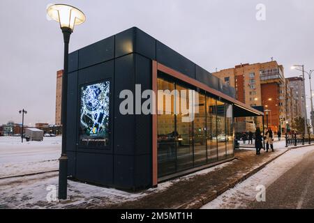 Astana, Kasachstan - 23. November 2022: Menschen warten auf öffentliche Verkehrsmittel. Beheizte Bushaltestellen mit Klimaanlage. Warm im Winter, kühl im Sommer. Stockfoto