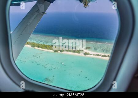 Flugzeugfenster mit wunderschönem Blick auf die Insel Malediven. Luxuriöser Sommerurlaub Tourismus Hintergrund, Blick aus dem Flugzeugfenster. Atollinseln Stockfoto