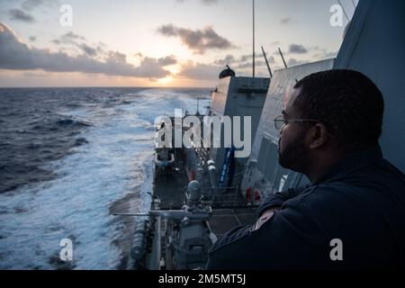 PHILIPPINE SEA (27. März 2022) Gunner's Mate 2. Class Taquan Taylor aus Mobile, Alabama, steht Wache auf dem Brückenflügel des Arleigh-Burke-Klasse-Guided-Raketenzerstörers USS Dewey (DDG 105) während der Teilnahme an Surface Warfare Advanced Tactical Training (SWATT). SWATT bietet der Flotte die Möglichkeit, die taktische Übung durchzuführen, die für erhöhte Letalität und taktische Fähigkeiten erforderlich ist. Stockfoto