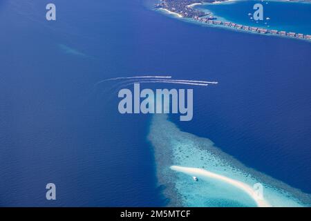 Landschaftsblick aus der Vogelperspektive über die Malediven Luxus Resort Villen mit Atoll Sandbank Insel. Jetskis haben Spaß in der Meereslagune. Luxuriöser Sommer Stockfoto