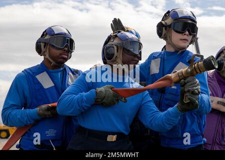 220328-N-IL330-1182 SAN DIEGO (28. März 2022) – Seeleute handhaben einen Feuerwehrschlauch während einer Feuerlöschübung auf dem Kampfdeck an Bord des Amphibienschiffs USS Tripoli (LHA 7), März 28. Tripolis ist ein Amphibienschiff der amerikanischen Klasse, das in San Diego Homeportiert ist. Stockfoto