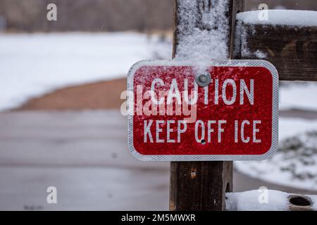 Eine Nahaufnahme eines Warnschilds mit der Aufschrift halten Sie Eis von Schnee bedeckt Stockfoto