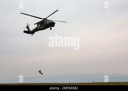 USA Soldaten der Armee, Einheit 2, Charlie Kompanie, 1. Bataillon, 169. Luftregiment, Virginia Nationalgarde, Durchführung einer Hochleistungs-Rettungsaufzug- oder HPU-Schulung in Camp Bondsteel, Kosovo, 28. März 2022. Die HPU-Vorrichtung ermöglicht es medizinischen Evakuierungsteams, Personen sicher aus Bereichen zu entfernen, in denen die Landung eines Flugzeugs nicht sicher oder nicht möglich ist. Stockfoto