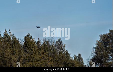 Eine Crew der Nationalgarde der Wisconsin Army UH-60 Black Hawk mit dem 1. Bataillon in Madison, Wisconsin, 147. Aviation Regiment-Zug, der am 28. März 2022 mit Bambi-Eimern in Fort McCoy, Wisconsin, Wasser auf Waldbrände wirft. Mitarbeiter der Feuerwehr von Fort McCoy, der Direktion für öffentliche Arbeiten, natürliche Ressourcen, der Wisconsin Abteilung für natürliche Ressourcen und Flugbesatzung sowie Black Hawk Helikopter des 1. Bataillons, 147. Luftfahrtregiment in Madison, Wisconsin, nahmen an der Feuerschulung während einer vorgeschriebenen Brandverbrennung Teil. Stockfoto