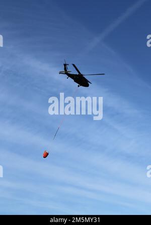 Eine Crew der Nationalgarde der Wisconsin Army UH-60 Black Hawk mit dem 1. Bataillon in Madison, Wisconsin, 147. Aviation Regiment-Zug, der am 28. März 2022 mit Bambi-Eimern in Fort McCoy, Wisconsin, Wasser auf Waldbrände wirft. Mitarbeiter der Feuerwehr von Fort McCoy, der Direktion für öffentliche Arbeiten, natürliche Ressourcen, der Wisconsin Abteilung für natürliche Ressourcen und Flugbesatzung sowie Black Hawk Helikopter des 1. Bataillons, 147. Luftfahrtregiment in Madison, Wisconsin, nahmen an der Feuerschulung während einer vorgeschriebenen Brandverbrennung Teil. Stockfoto