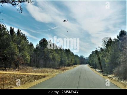 Eine Crew der Nationalgarde der Wisconsin Army UH-60 Black Hawk mit dem 1. Bataillon in Madison, Wisconsin, 147. Aviation Regiment-Zug, der am 28. März 2022 mit Bambi-Eimern in Fort McCoy, Wisconsin, Wasser auf Waldbrände wirft. Mitarbeiter der Feuerwehr von Fort McCoy, der Direktion für öffentliche Arbeiten, natürliche Ressourcen, der Wisconsin Abteilung für natürliche Ressourcen und Flugbesatzung sowie Black Hawk Helikopter des 1. Bataillons, 147. Luftfahrtregiment in Madison, Wisconsin, nahmen an der Feuerschulung während einer vorgeschriebenen Brandverbrennung Teil. Stockfoto