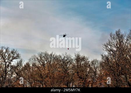 Eine Crew der Nationalgarde der Wisconsin Army UH-60 Black Hawk mit dem 1. Bataillon in Madison, Wisconsin, 147. Aviation Regiment-Zug, der am 28. März 2022 mit Bambi-Eimern in Fort McCoy, Wisconsin, Wasser auf Waldbrände wirft. Mitarbeiter der Feuerwehr von Fort McCoy, der Direktion für öffentliche Arbeiten, natürliche Ressourcen, der Wisconsin Abteilung für natürliche Ressourcen und Flugbesatzung sowie Black Hawk Helikopter des 1. Bataillons, 147. Luftfahrtregiment in Madison, Wisconsin, nahmen an der Feuerschulung während einer vorgeschriebenen Brandverbrennung Teil. Stockfoto